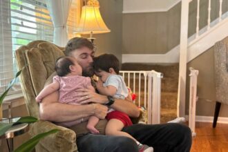 U.S. Marine Corps veteran Adrian Clouatre holds his 3-month-old daughter Lyn and his nearly 2-year-old son Noah at their home in Baton Rouge, Louisiana, June 17, 2025.
