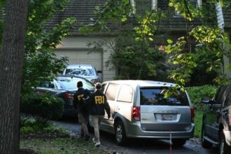 FBI agents walk outside the home of John Bolton