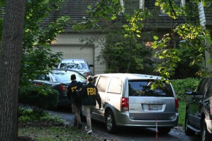 FBI agents walk outside the home of John Bolton